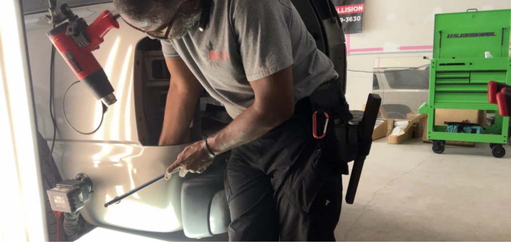 Technician performing paintless dent repair on vehicle panel using specialized tools in Dallas-Fort Worth area