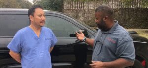Paintless dent repair technician inspecting vehicle with customer in Plano Texas pre-purchase inspection service